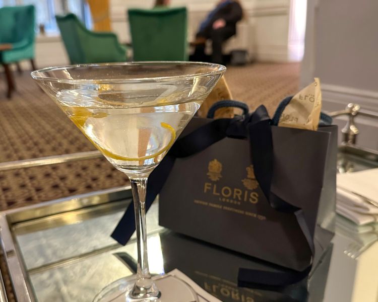 a martini next to a perfume shopping bag on glass table in exclusive bar