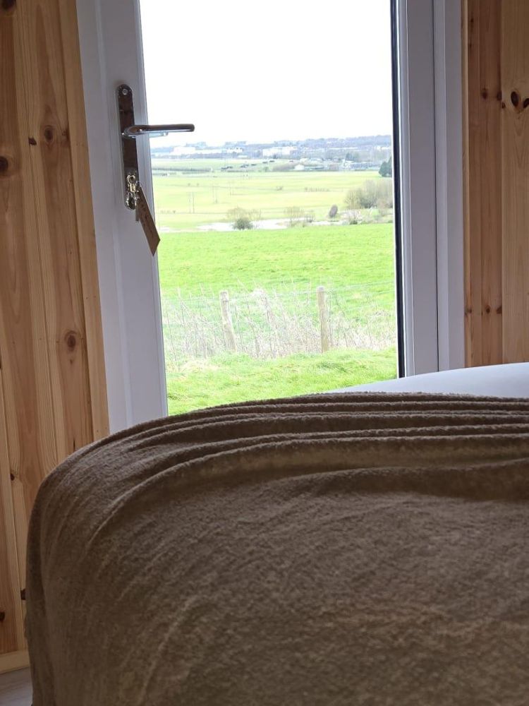 a view looking out of a glamping pod onto countryside on a stonehenge unique stay