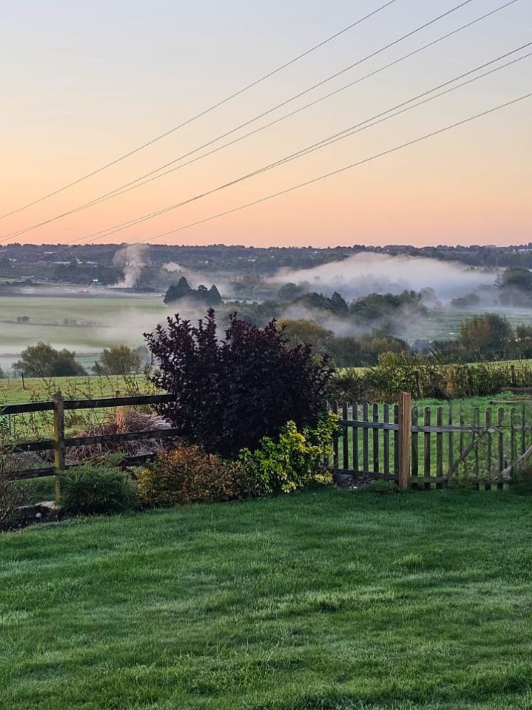 low lying cloud at sunrise over the countryside seen on a stonehenge unique stay in a glamping pod