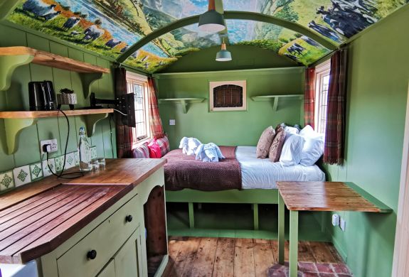 Looking at the bed area from the kitchen inside the shepherds hut used for short stays near stonehenge