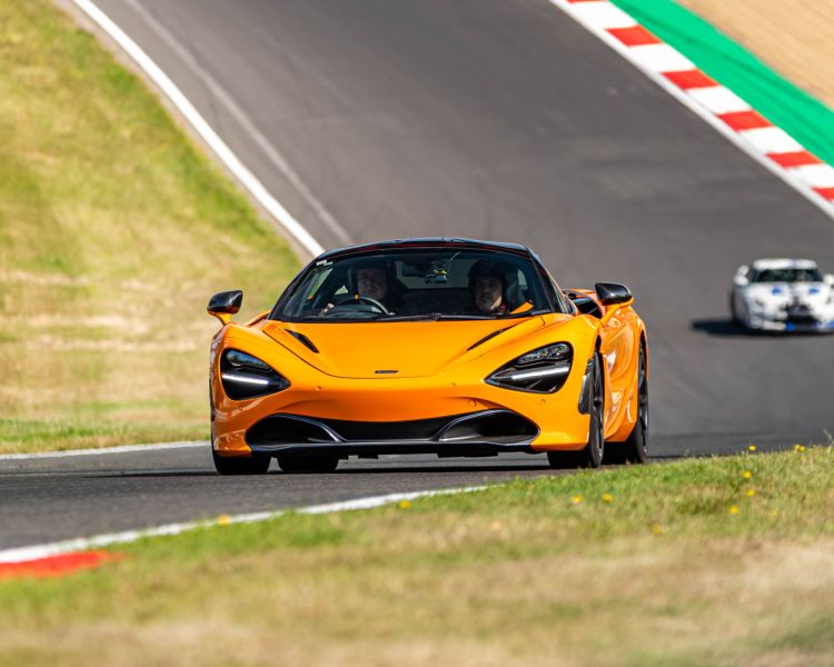 an orange supercar on a race track for a supercar vs classic car driving experience