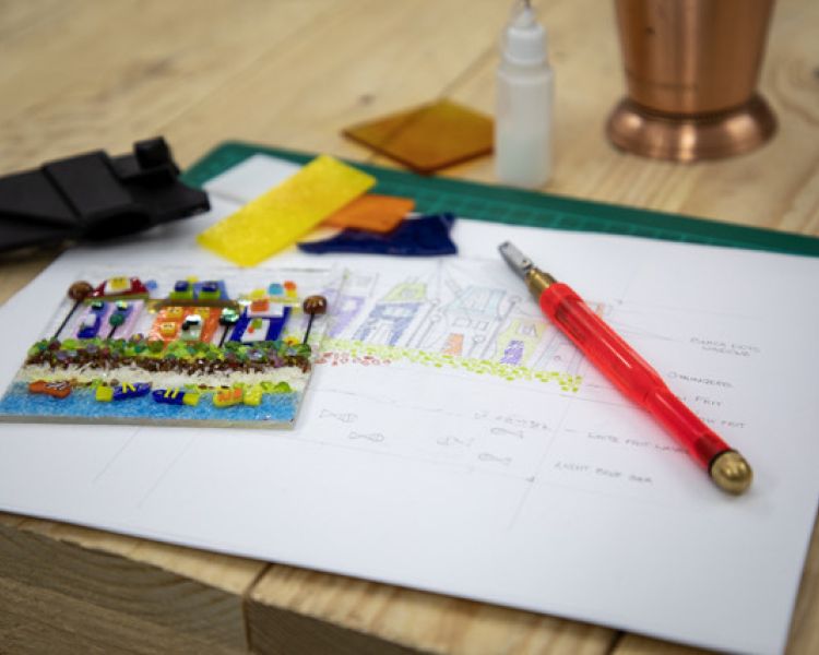 planning sketch for fused glass design on table with tools and materials