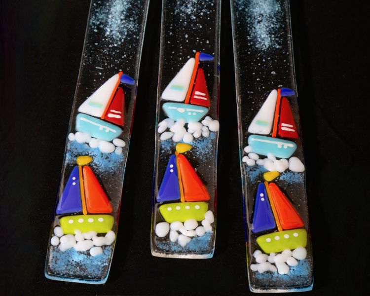 close up of three glass sun catchers with a coloured sailboat design