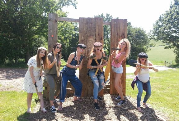 group of women posing in front of wooden boards holding axes as part of an axe throwing experience