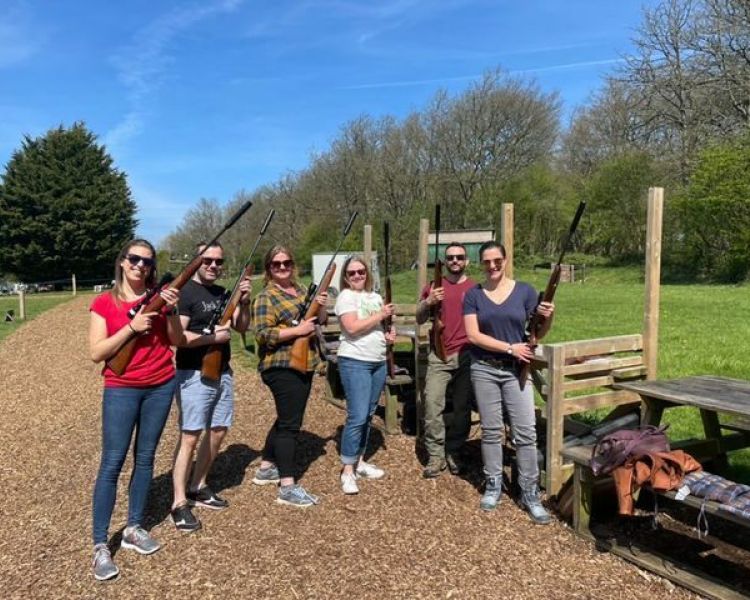 group of people posing for a photo holding air rifles as part of an air rifle shooting experience