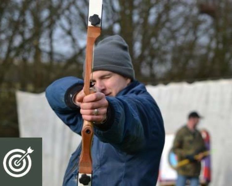 man holding a bow and arrow aiming towards the camera as part of an archery experience