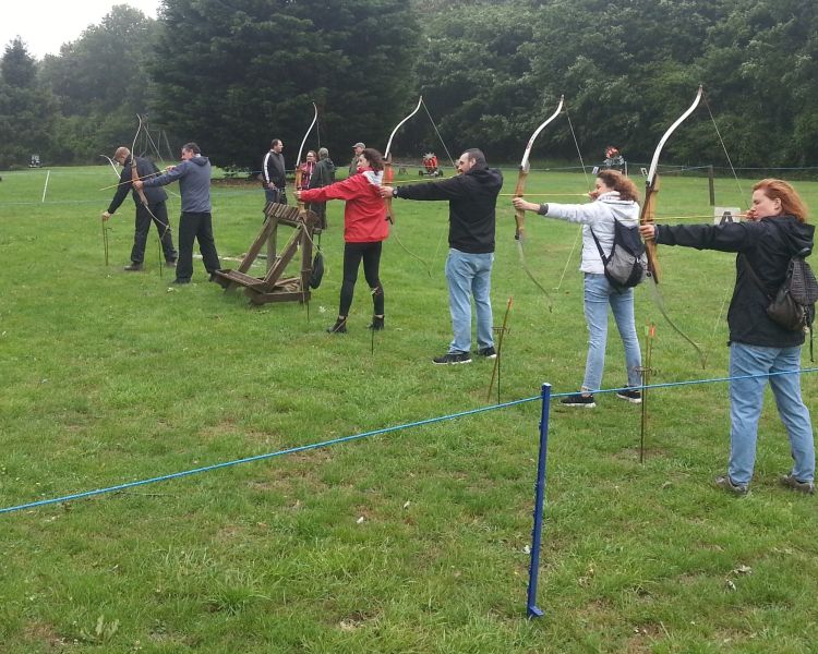 a row of people aiming bows and arrows at targets as part of an archery experience