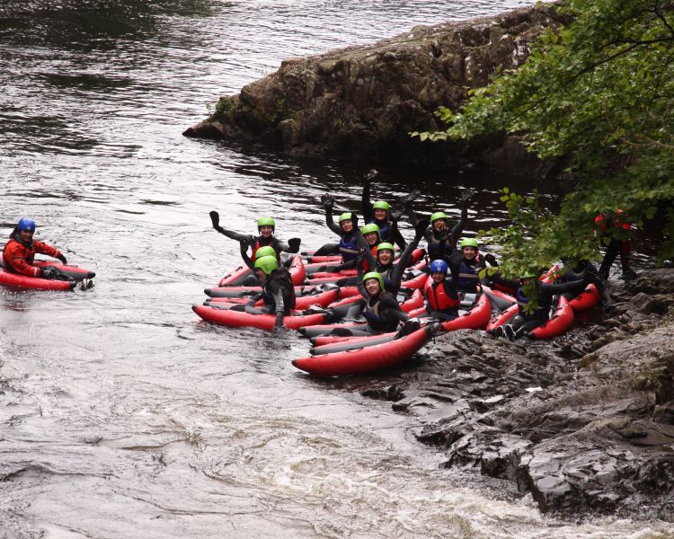 group of people on the side of a river getting ready for a river bugging experience on the river tummel in scotland