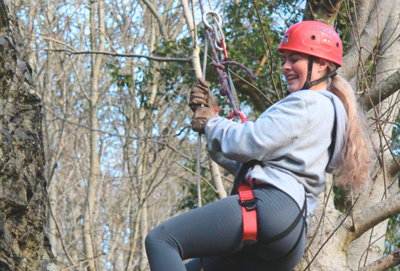 woman hanging in the trees on an abseiling experience in wales