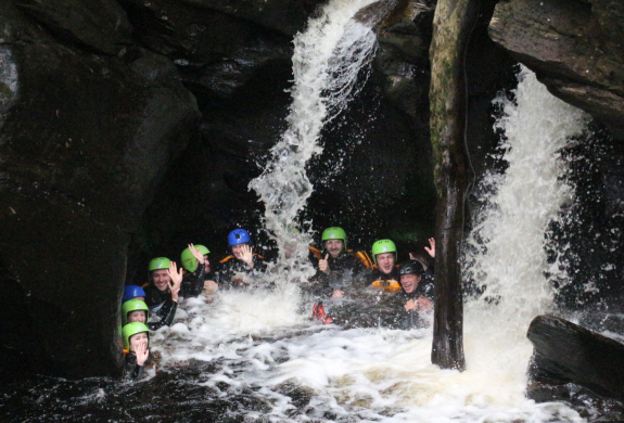 group of people in water at the bottom of a canyon on a canyoning experience in scotland