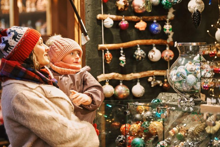 mum and young daughter looking at decorations at a christmas market