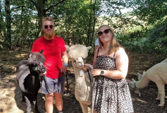 man and a woman standing next to alpacas on an alpaca walk experience