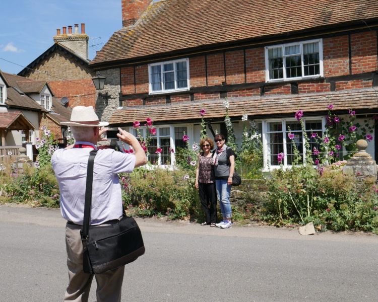 Two ladies posing for photo infront of cottage used for filming seen on a midsomer murders coach tour