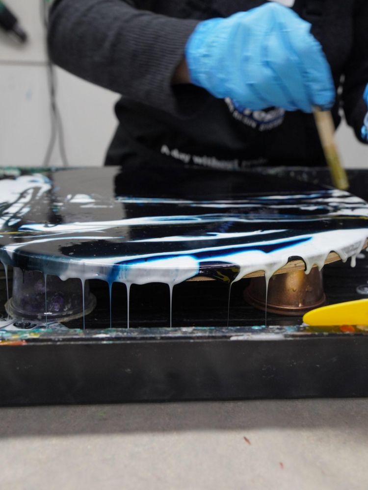 person painting resin onto board to make resin art