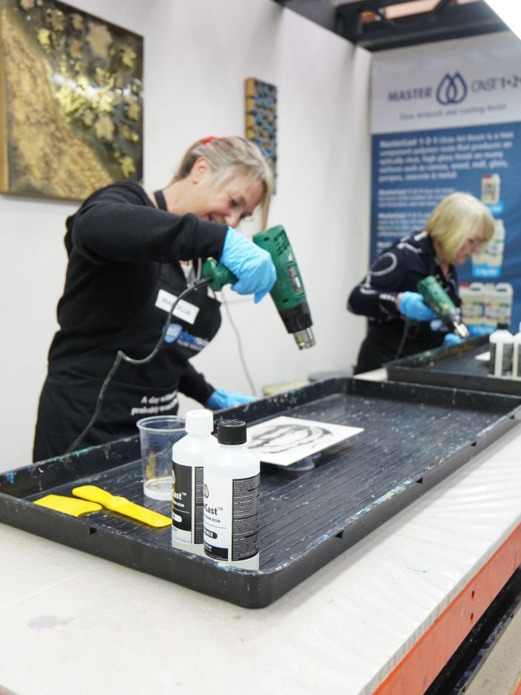 Applying heat gun to remove bubbles from resin art