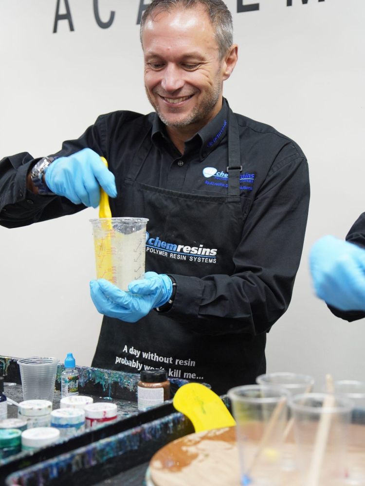 man smiling whilst mixing resin in cup to make resin art