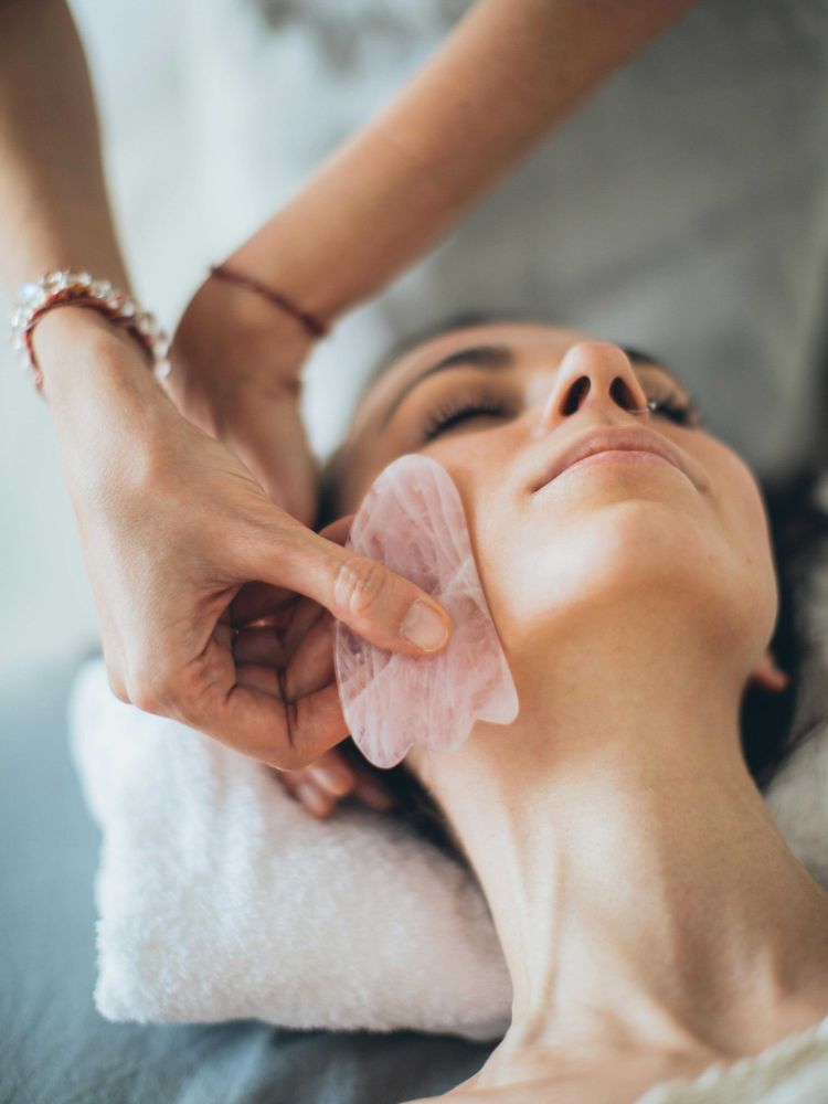 woman having a facial massage with gua sha tool
