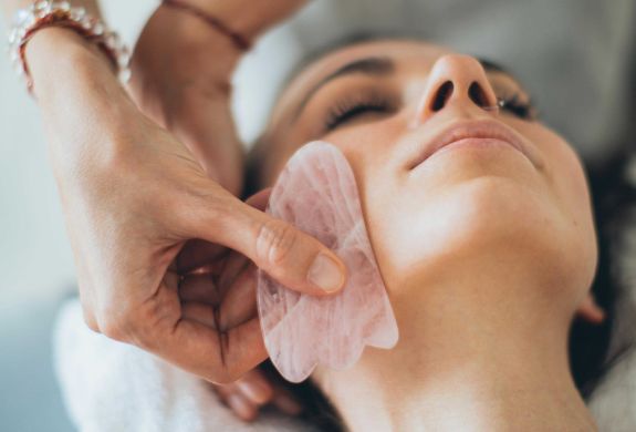 woman having a facial massage with gua sha tool