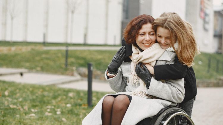 Daughter hugging mother in wheelchair