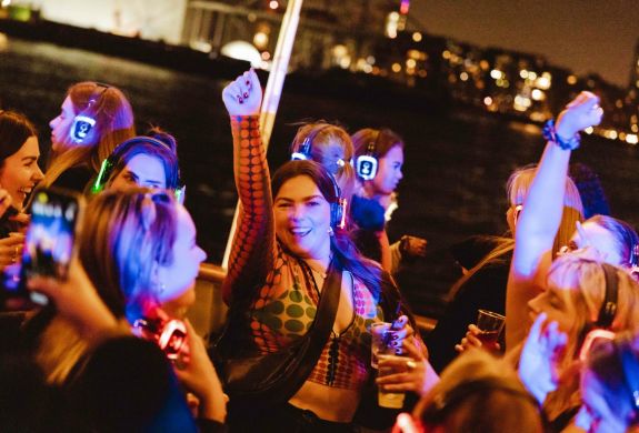 happy party goers on a silent sounds party river cruise on the thames in london