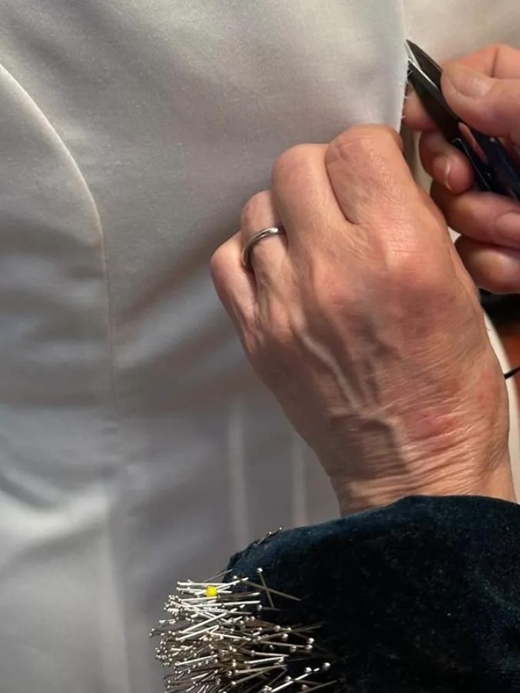 a garment being fitted on a woman by a designer in savile row london