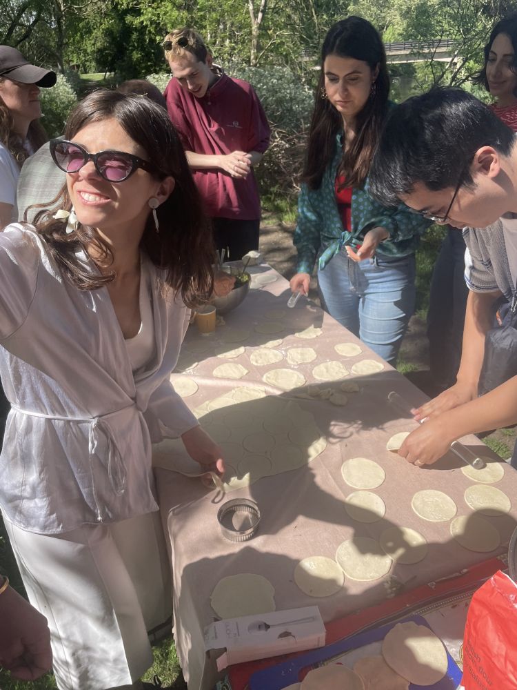 People making chinese style dumplings at an outdoor kitchen