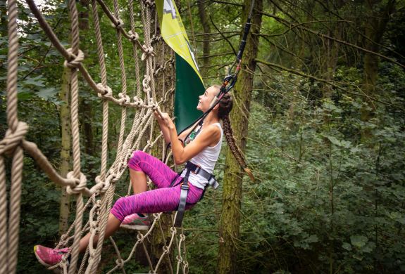 woman climbing nets on go ape treetop challenge course