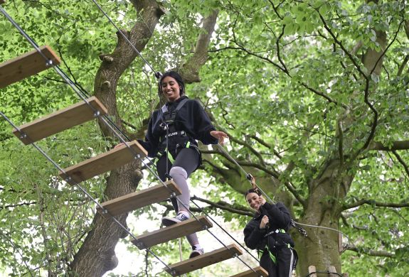two girls walking the rope bridge on treetop adventure plus course at go ape
