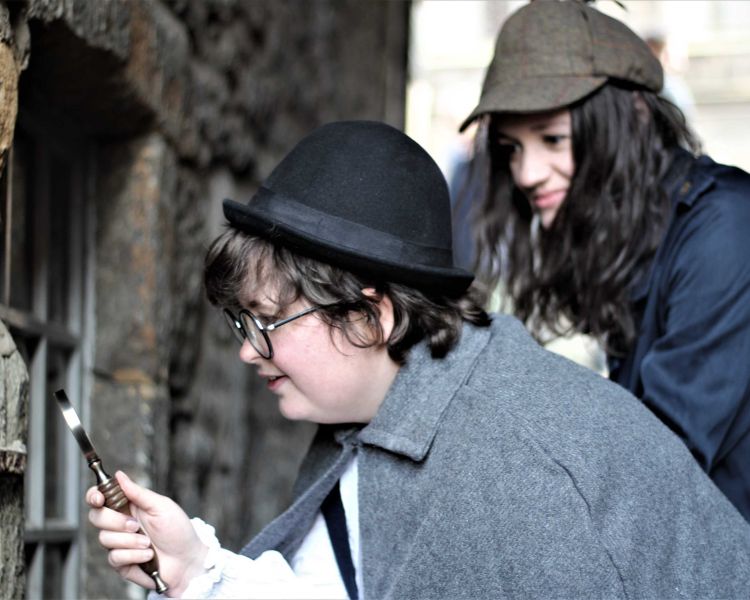 2 people dressed as sherlock holmes looking for clues on a sherlock holmes experience day in edinburgh