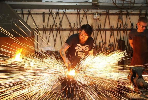 Man striking hot metal with sparks flying