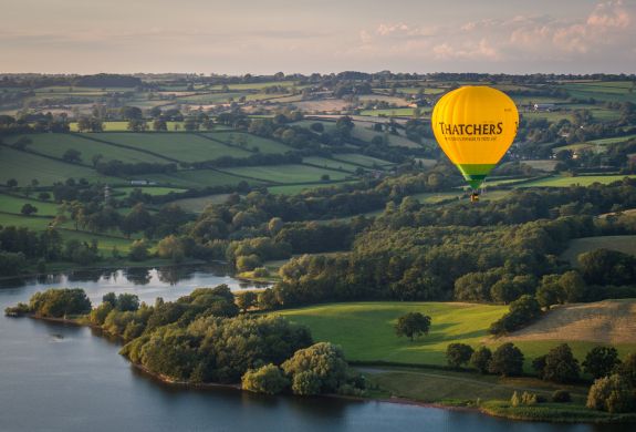 Hot air balloon flying over kent countryside and lake