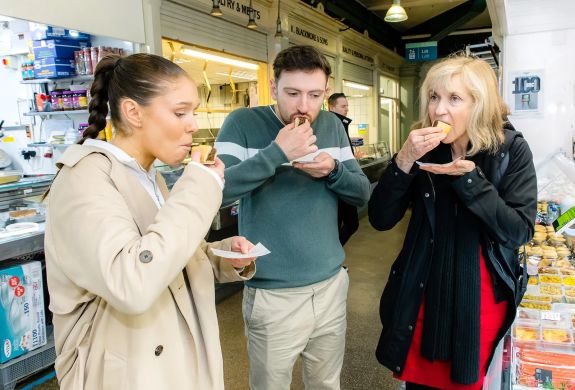 Tour group sampling food in market on welsh food tour