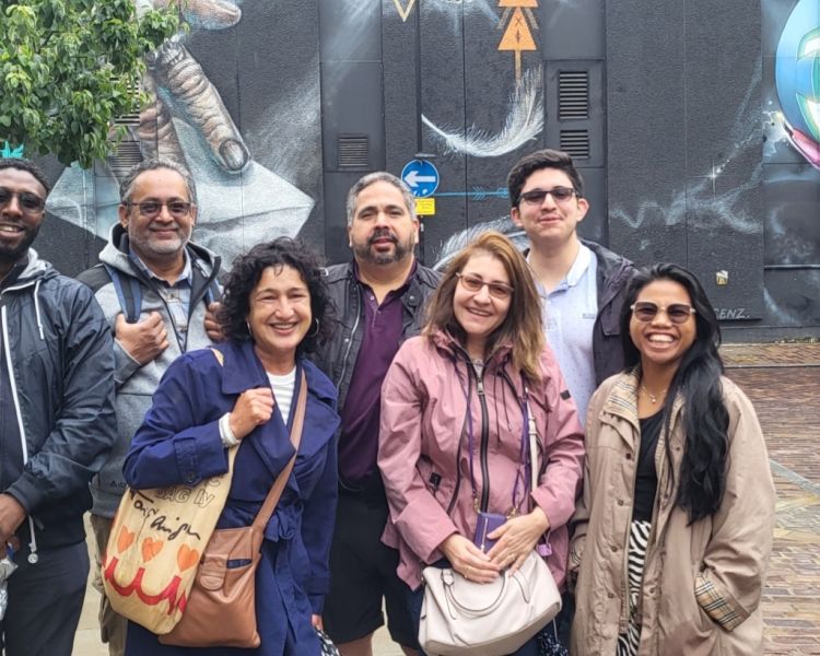 people posing for a photo in front of wall murals on the taste of diversity tour exploring london's street art and food