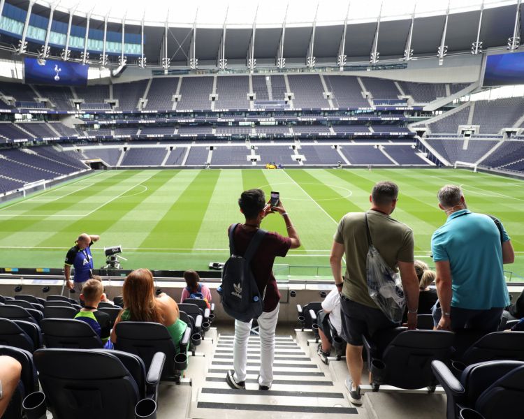 visitors in the stands overlooking the pitch on the tottenham hotspur stadium tour in london