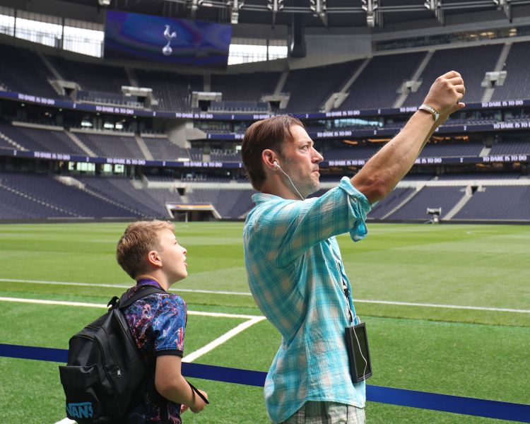 visitors taking photos of the pitch on the tottenham hotspur stadium tour in london