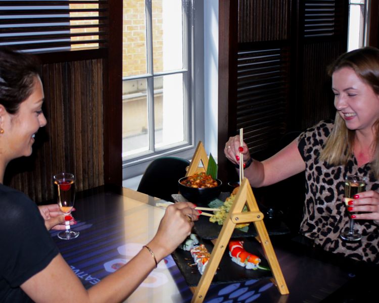 Two ladies eating an asian style afternoon tea with chopsticks