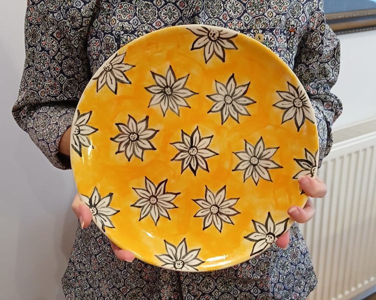 lady holding a plate painted with flowers