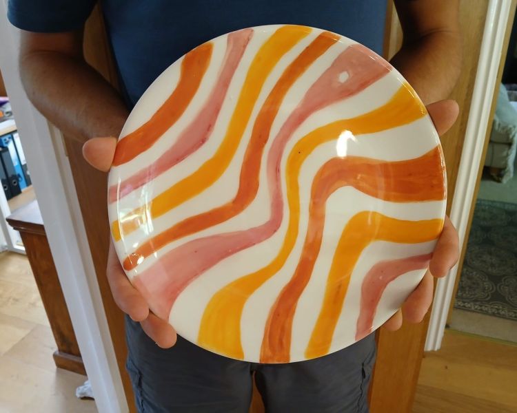 man holding a plate painted in retro swirls