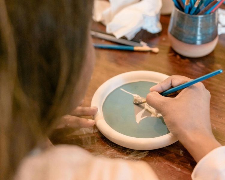 woman painting a small side plate