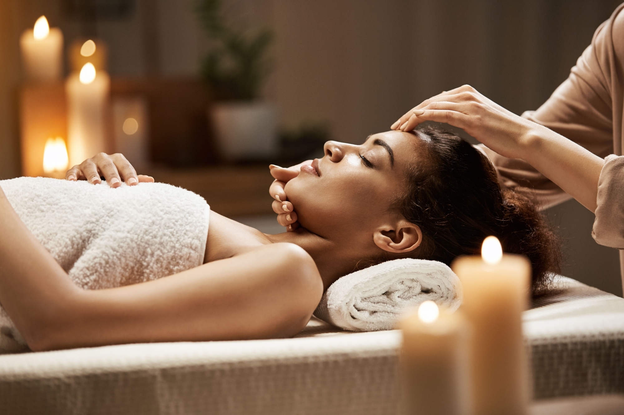 Attractive african woman enjoying face massage spa salon min