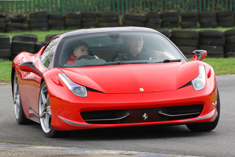 young boy on a junior supercar experience in a red supercar