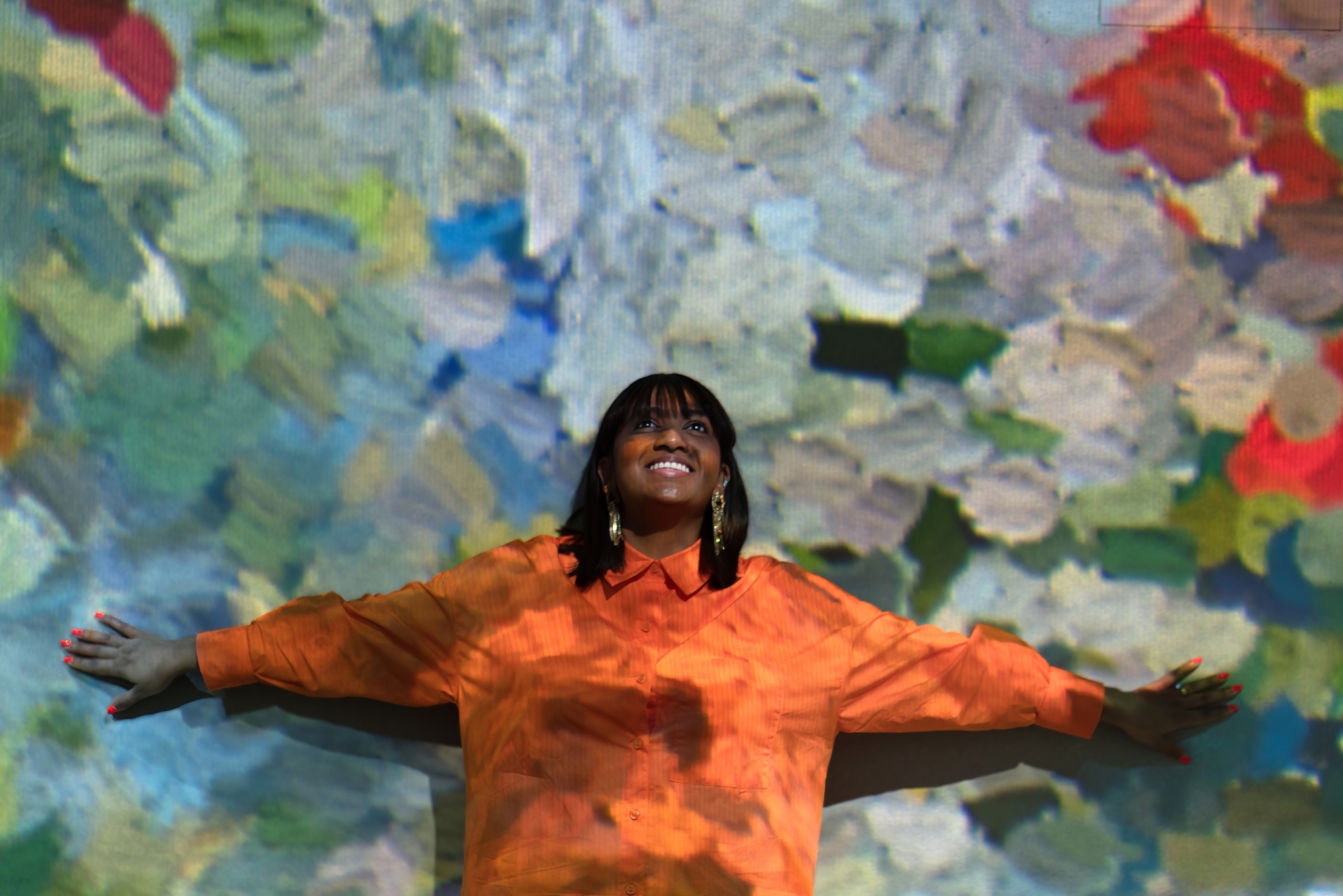 woman standing against a wall at the frameless immersive art exhibition in london