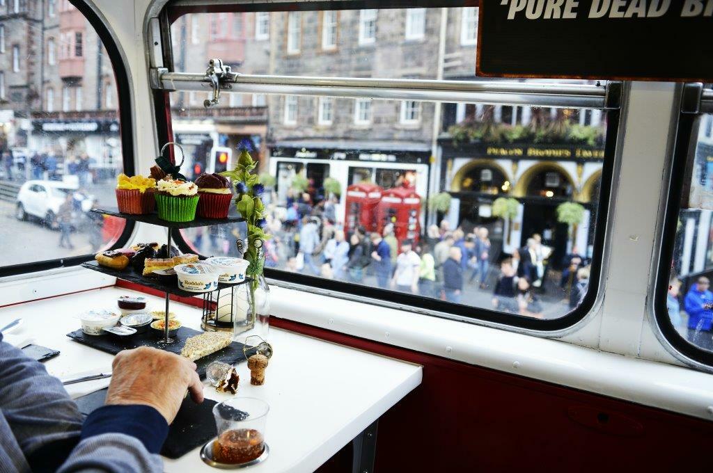 person enjoying afternoon tea looking through the windows on the red bus bistro afternoon tea tour