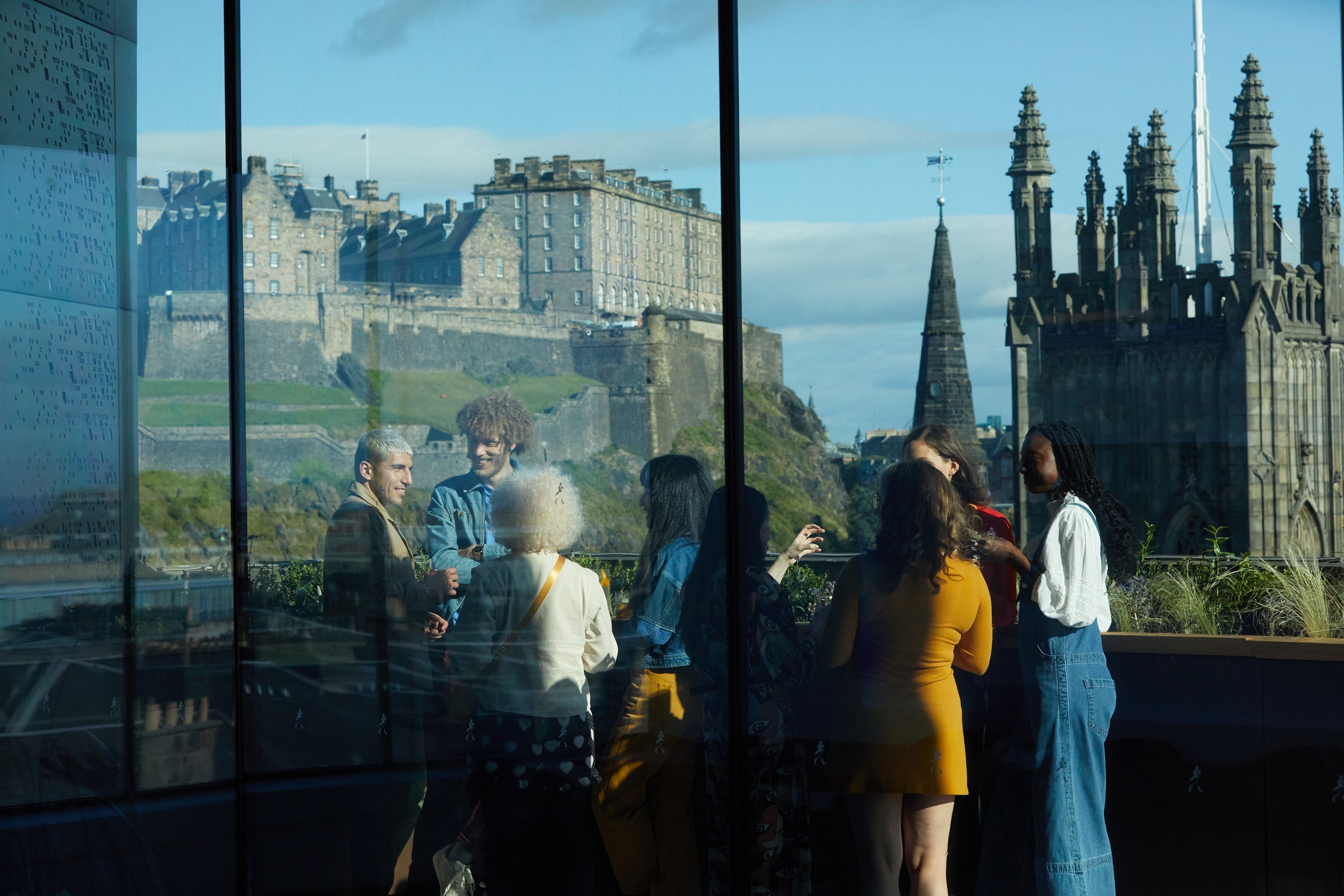 group of people enjoying a drink on the balcony overlooking edinburgh castle