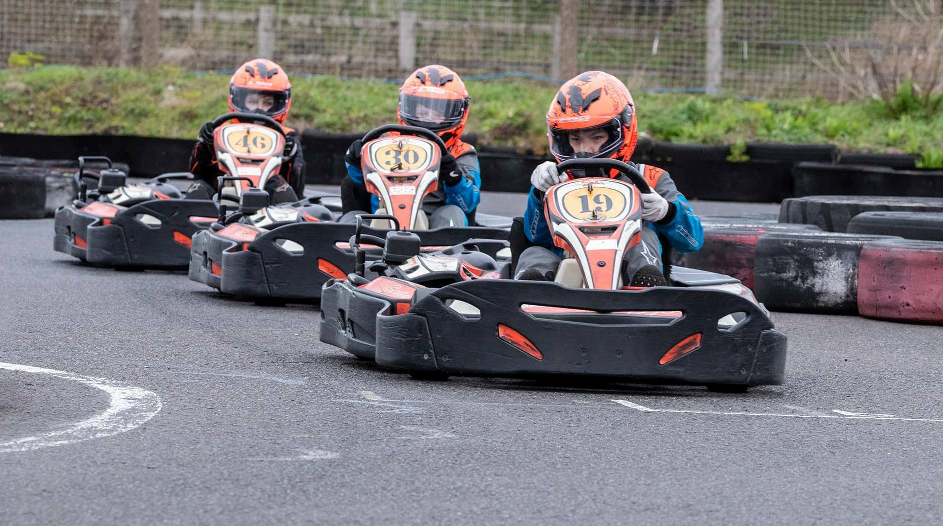 three people in a go kart race on a track
