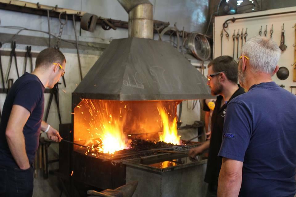 People heating up metal in forge on blacksmith experience